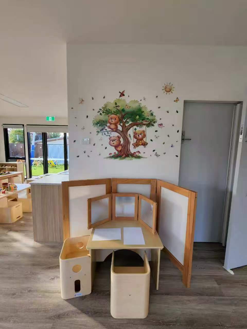 Toddler atelier with three-panel easel and woodland wall mural
